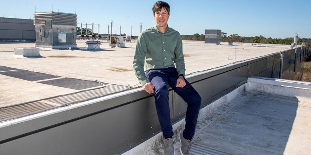 a tall man sitting on top of a flat roof building
