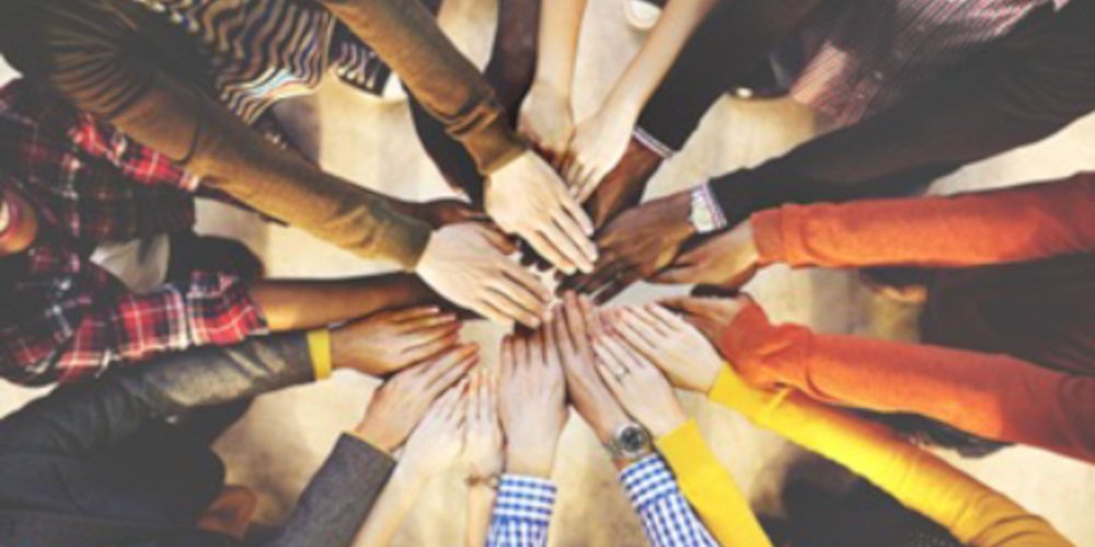 a group of people combine their hands into a circle