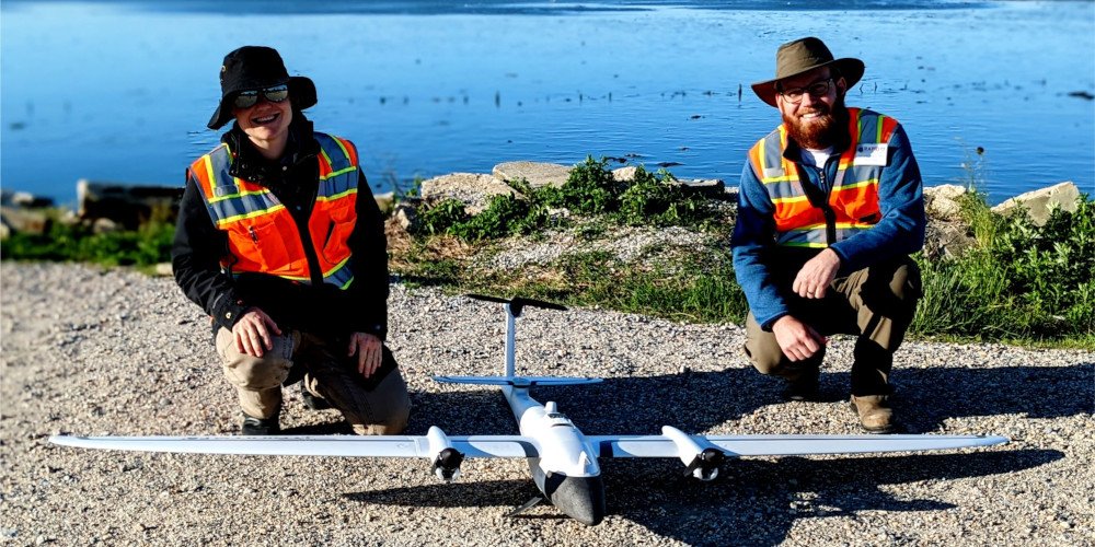 2 men kneeling by a small drone