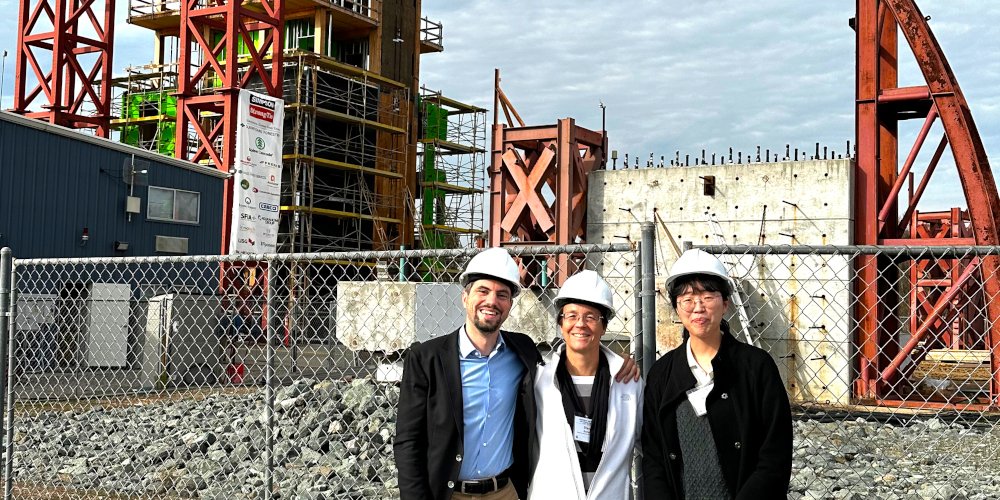 3 people wearing hardhats in front of a construction site