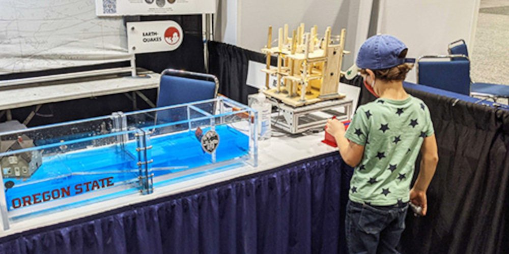 a child in front of a small model of a wave pool and a shake table