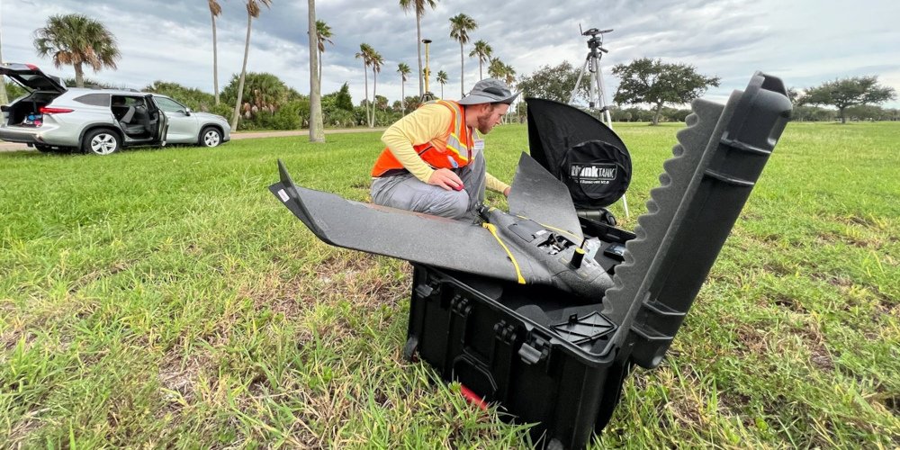 a man removing a drone from its case in the middle of a field
